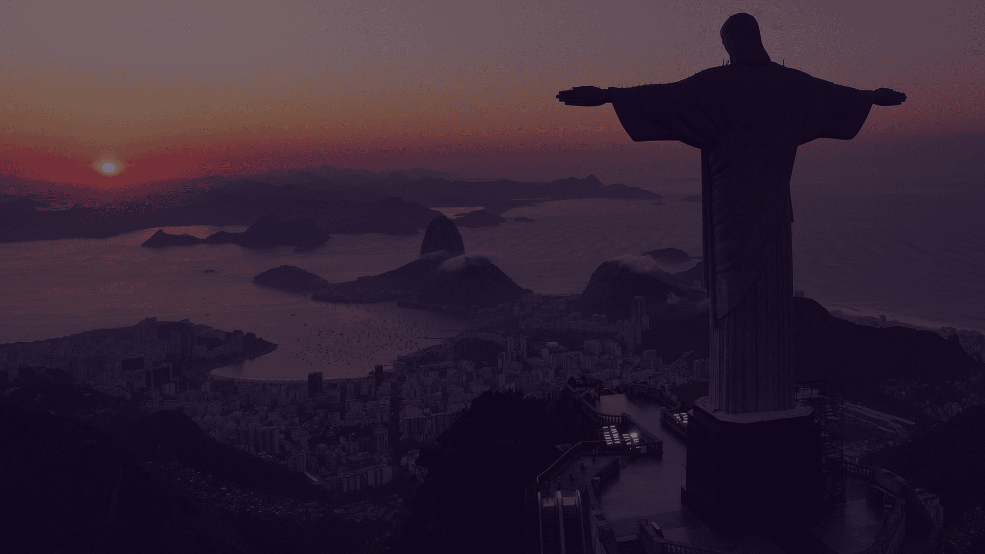 Silhouette of Christ the Redeemer statue overlooking Rio de Janeiro at sunset.