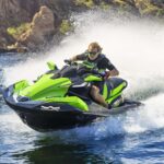 A person rides a green jet ski on choppy water.