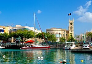 Sailboats docked near historic buildings under a clear blue sky.