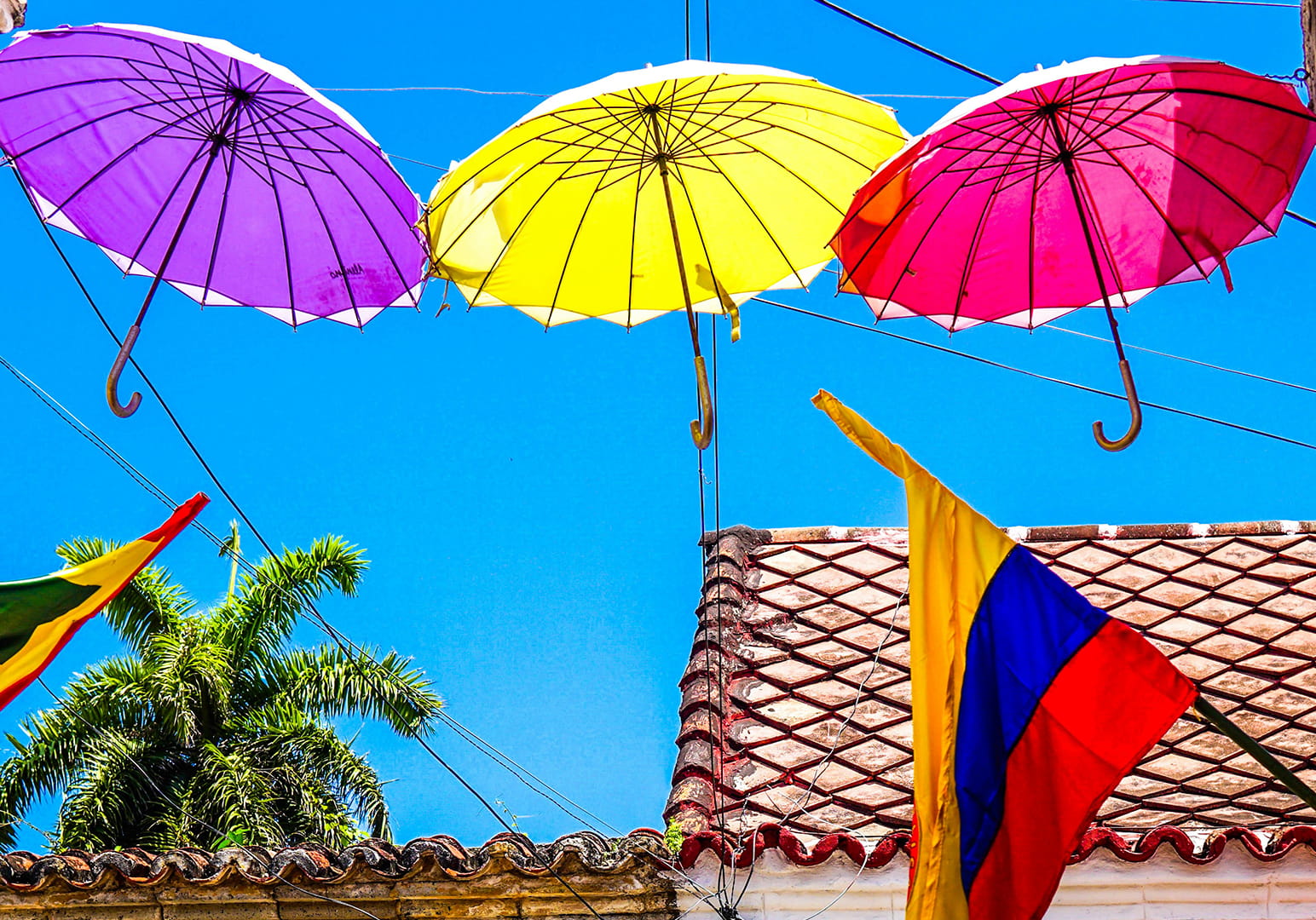 Colorful umbrellas and a flag brighten a sunny rooftop scene.
