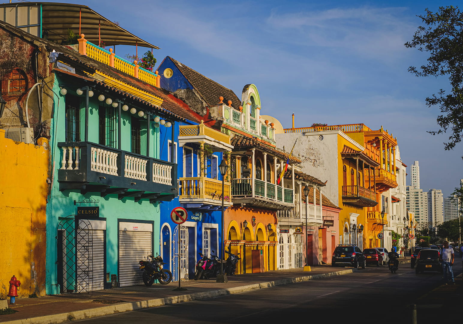 Colorful colonial buildings line a sunlit street under a clear blue sky.