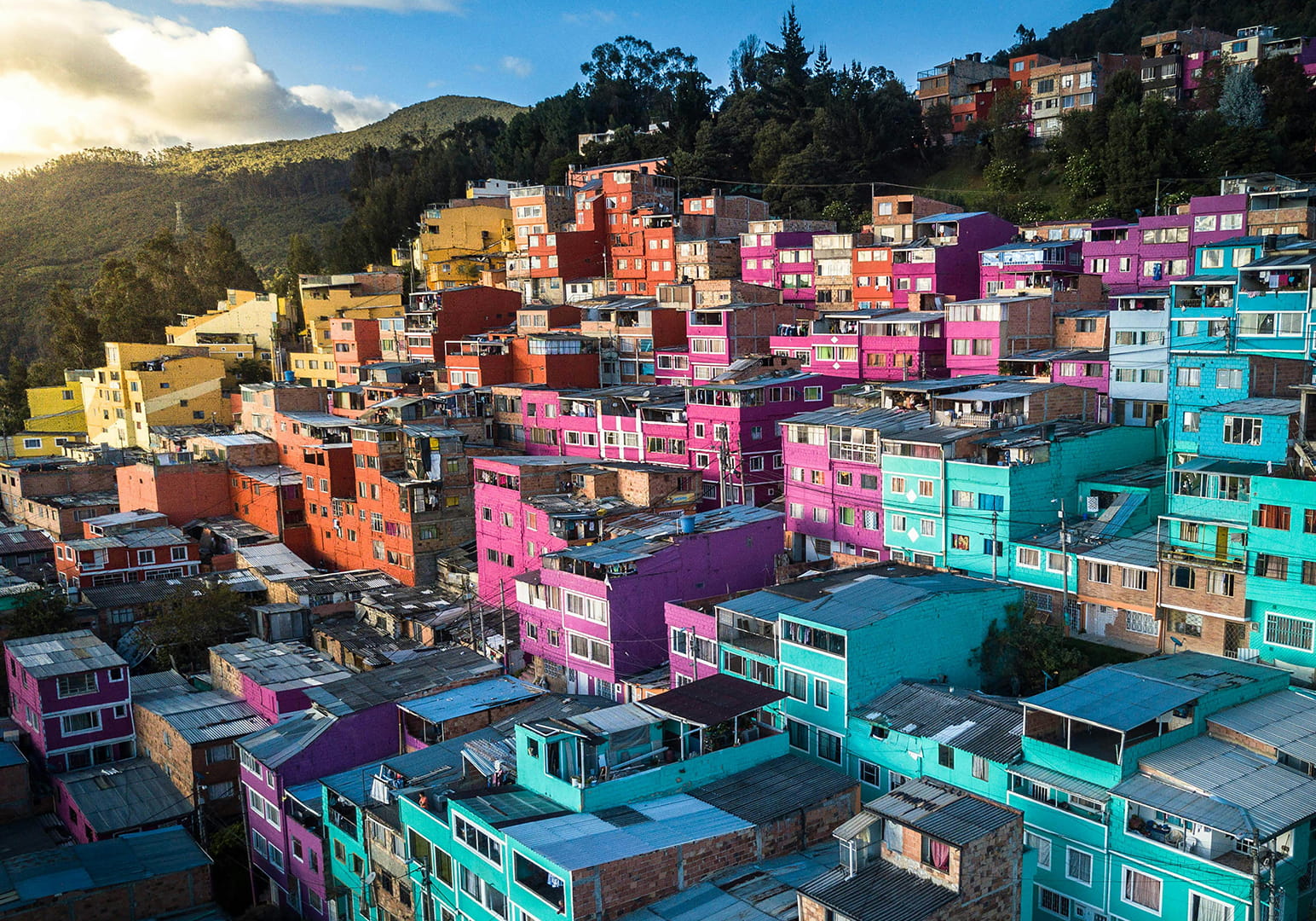 Colorful houses densely packed on a hillside under a sunny sky.