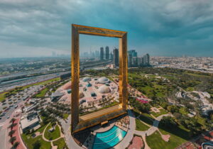 A giant golden picture frame overlooking a cityscape with skyscrapers and greenery.