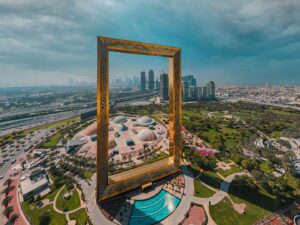A giant golden picture frame overlooking a cityscape with skyscrapers and greenery.