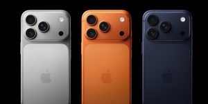 Three iPhones in silver, orange, and black with triple cameras.